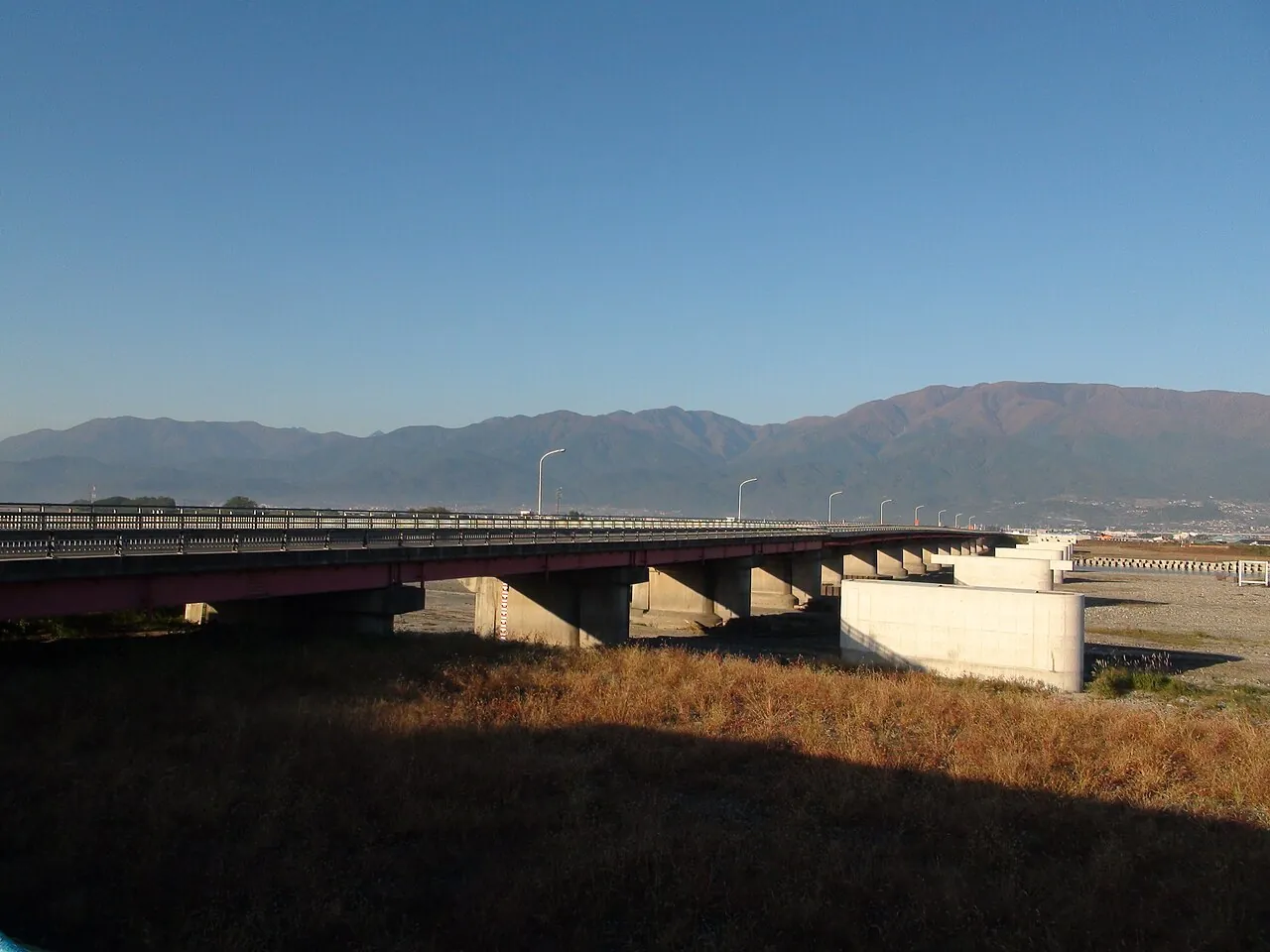 河原に架かる長い橋と、その向こうに連なる山々