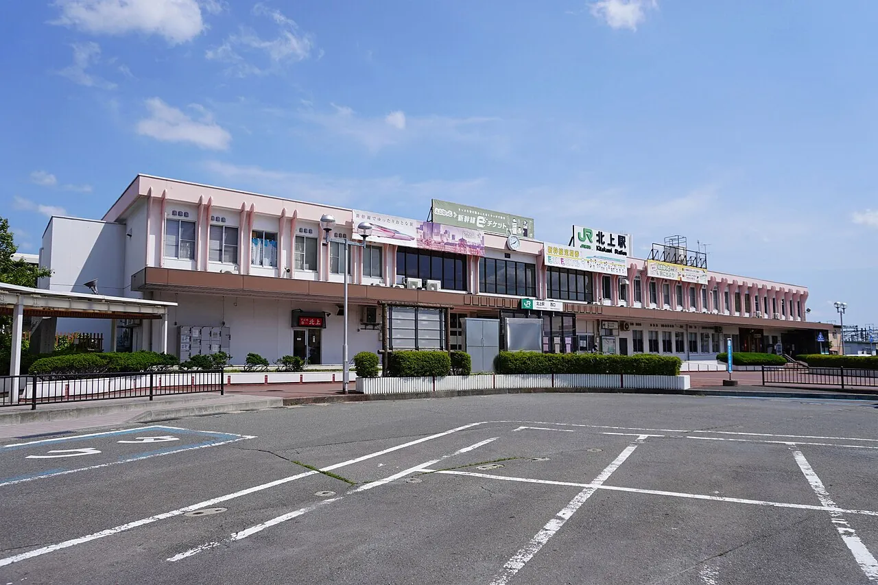 青空の下に建つ北上駅の西口の駅舎と、その前の広場